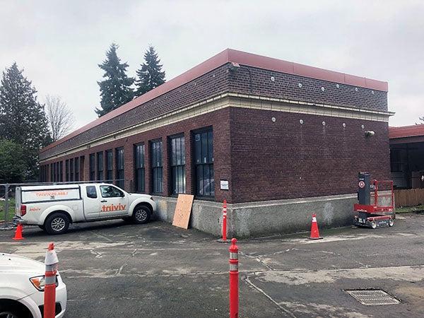 the corner of a brick building with a flat roof. a truck sits in front