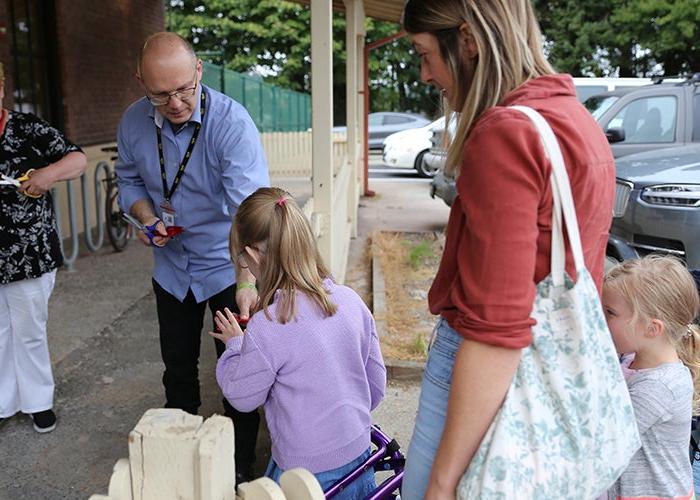 a man hands something to a child while and adult and another child stand by